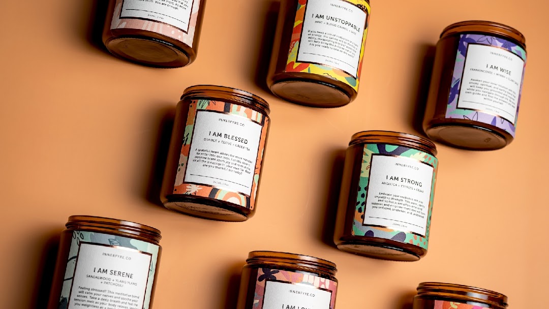 A collection of Innerfyre Co. scented candles with unique labels and affirmations.