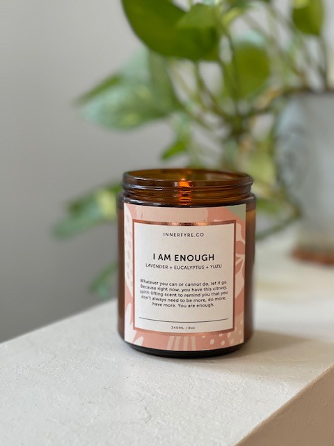A close-up of an Innerfyre Co. 'I Am Enough' candle with lavender, eucalyptus, and yuzu scents.