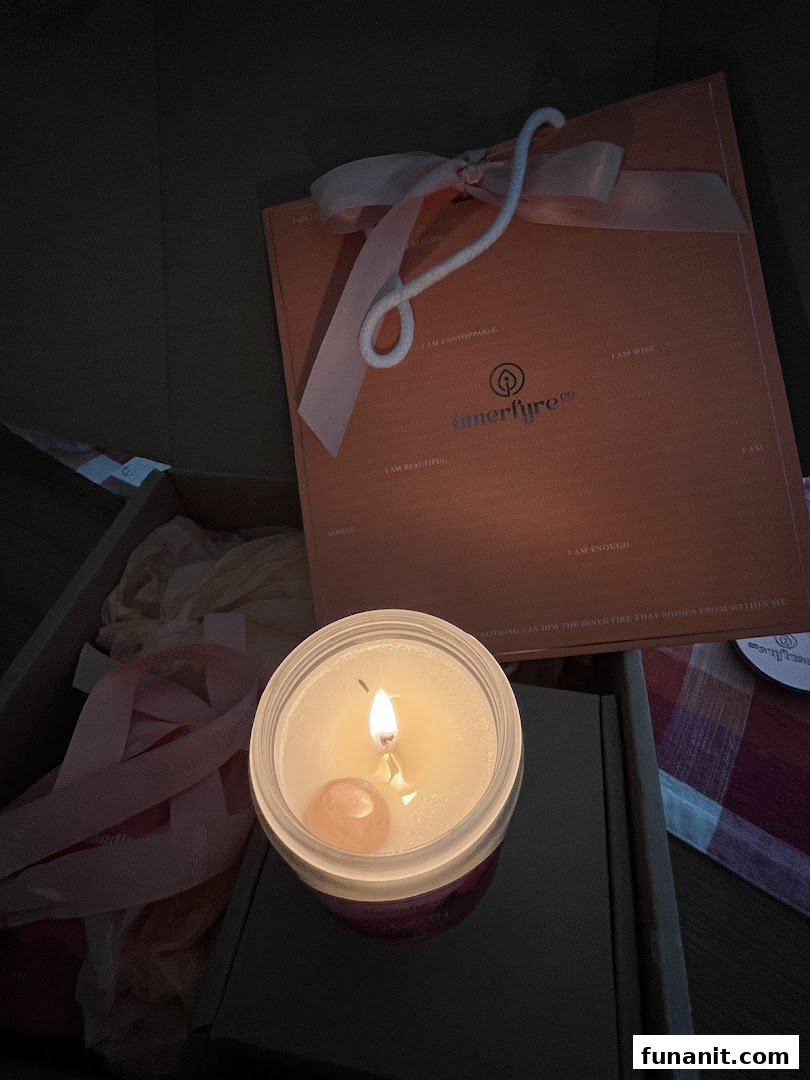 A lit Innerfyre Co. candle with a crystal, alongside a branded gift box, showcasing a product experience.