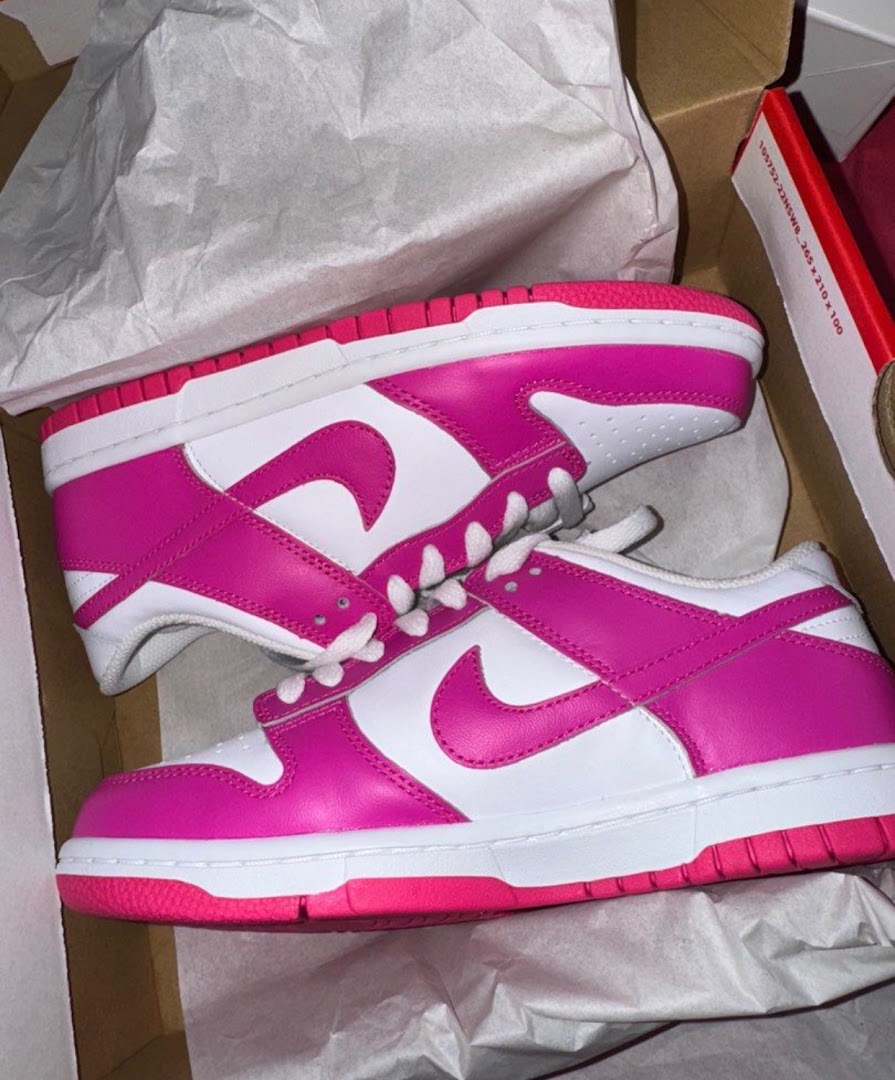 A pair of vibrant pink and white sneakers displayed in an open shoe box.