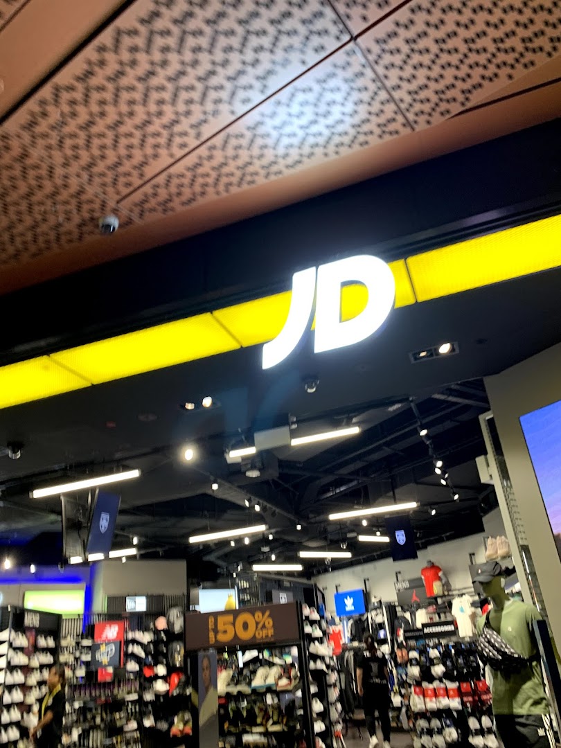 The entrance of JD Sports, showcasing its prominent logo and a view into the vibrant retail space.