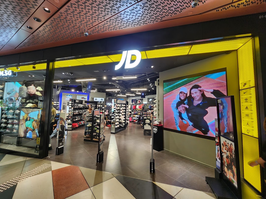 The vibrant entrance of JD Sports, featuring its logo, a large digital display, and a view into the retail space.