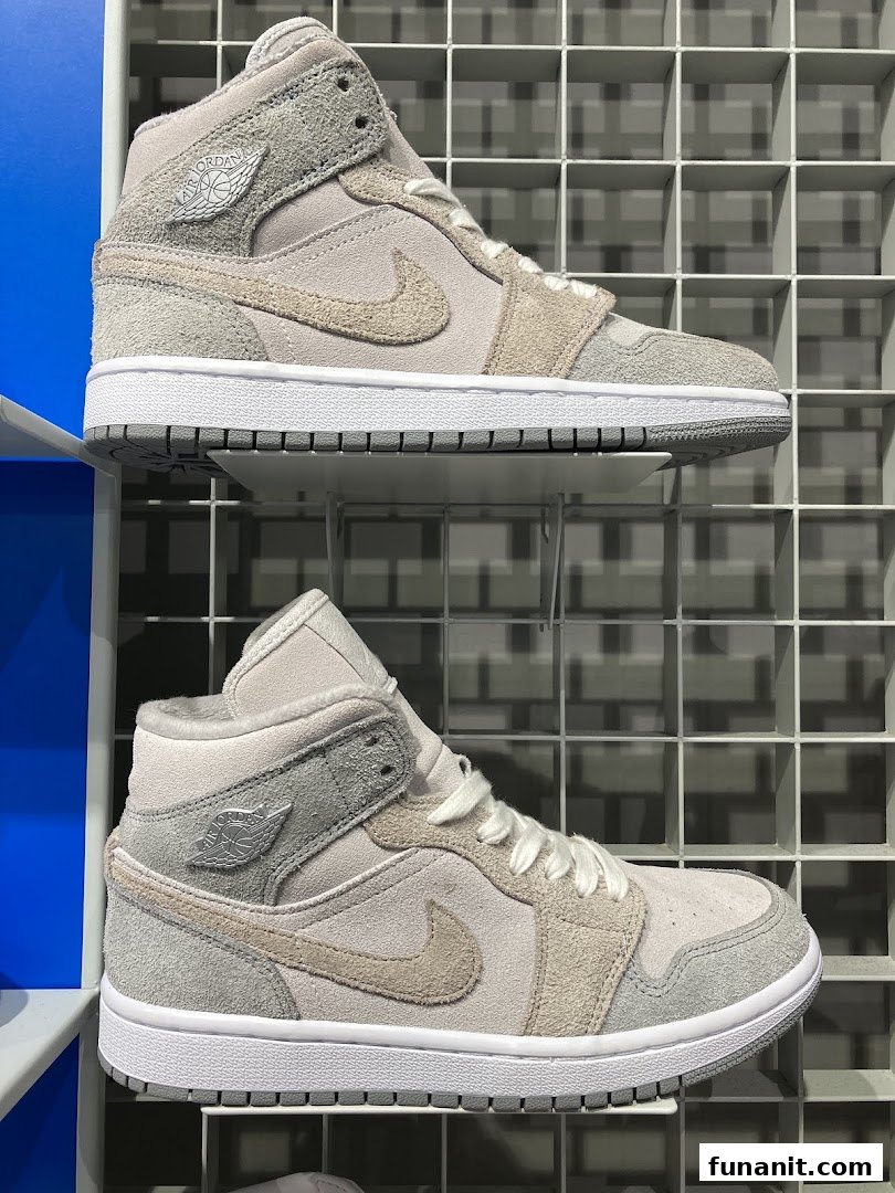 Two pairs of stylish grey and beige sneakers are displayed on a grid shelf.