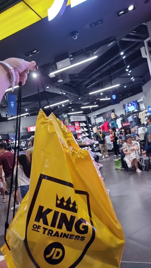 Interior view of JD Sports with customers and a prominent 'King of Trainers' shopping bag.