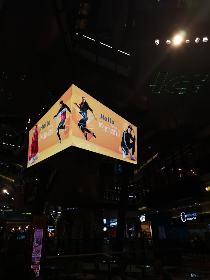A large digital display featuring active lifestyle visuals in a modern, dimly lit mall interior.