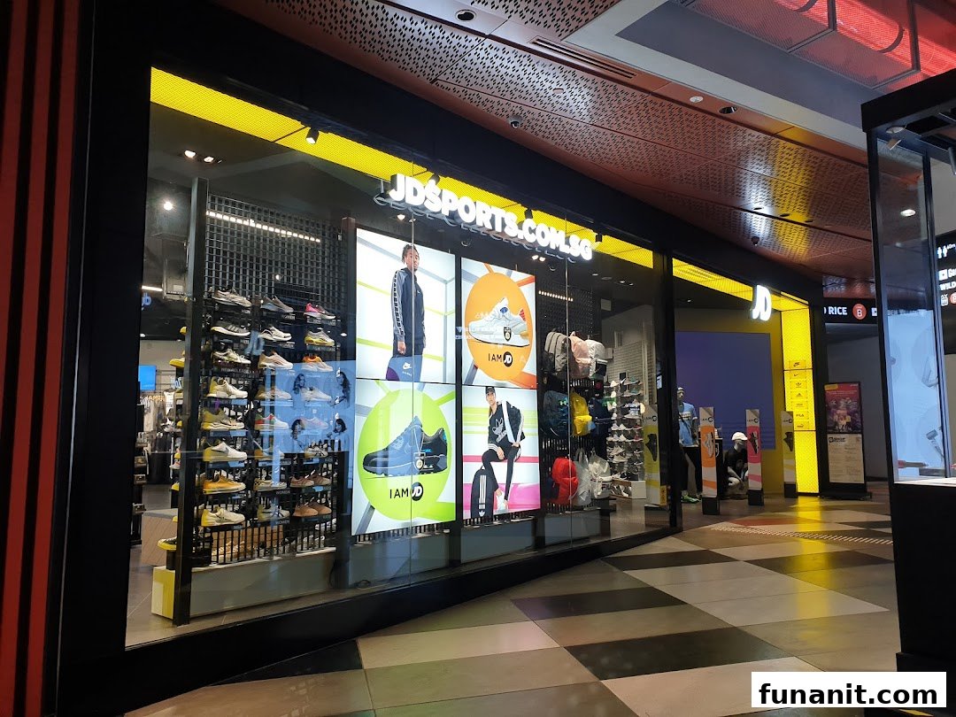 The brightly lit storefront of JD Sports, showcasing athletic footwear displays and digital screens.