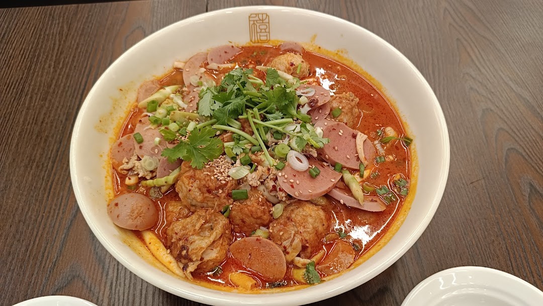 A vibrant bowl of spicy Chinese hot pot with various meats, vegetables, and broth.
