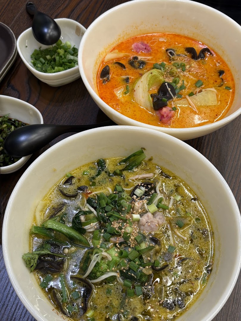 Two vibrant bowls of delicious noodles or soup, one red and one green, served with various toppings.