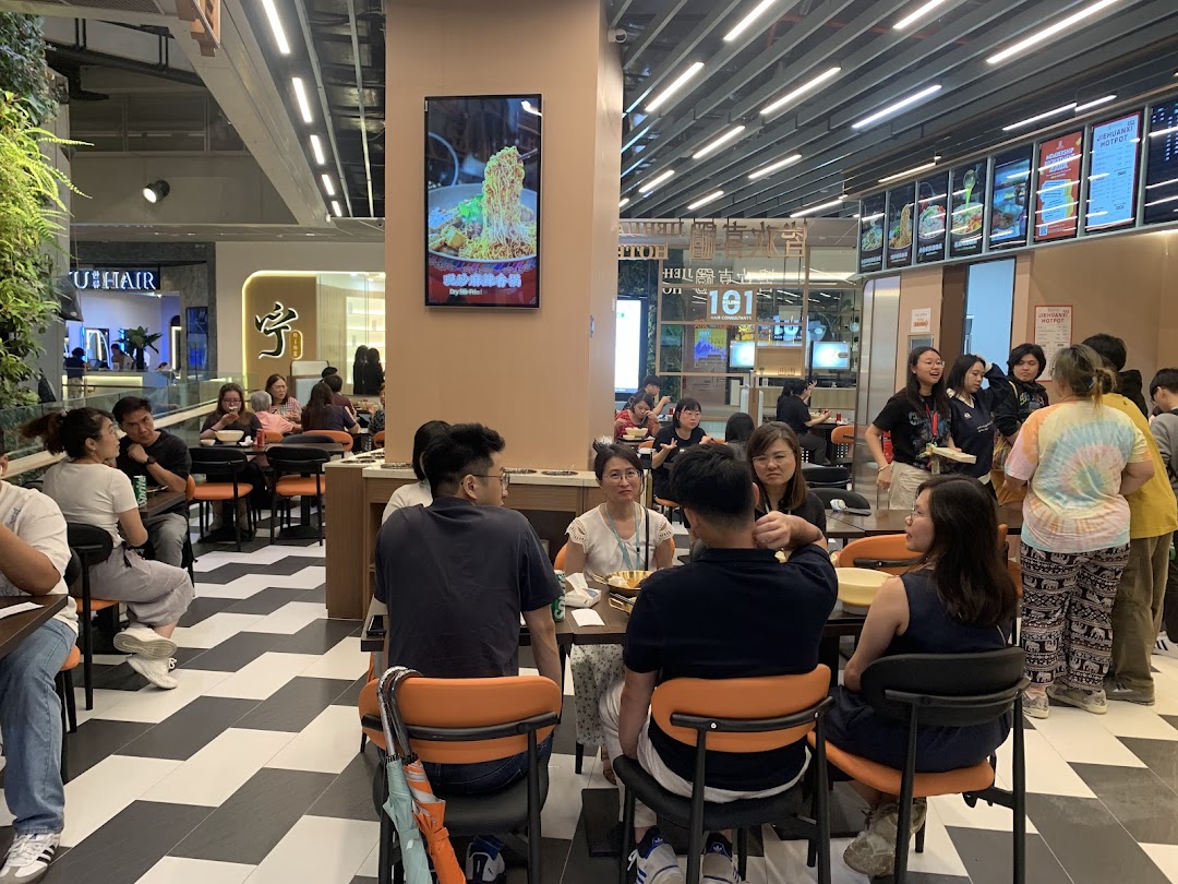 Customers dine and wait in a bustling, modern food court or restaurant setting with a digital menu display.