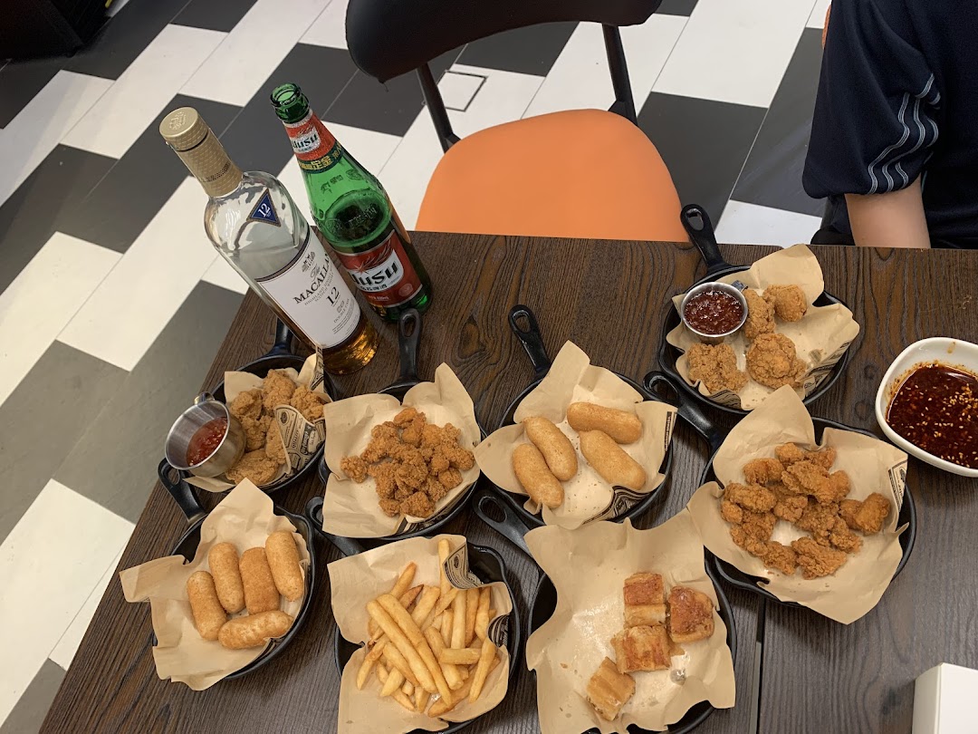 A table filled with various fried snacks, including chicken, fries, and other items, accompanied by whisky and beer.
