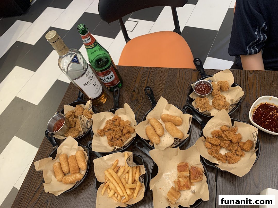 A table filled with various fried snacks, including chicken, fries, and other items, accompanied by whisky and beer.