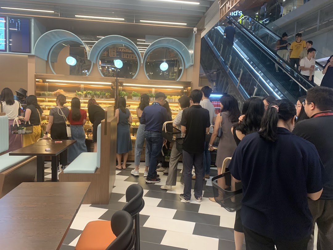 Customers browse fresh baked goods and food items inside Jie Huan Xi, a bustling shop with seating.