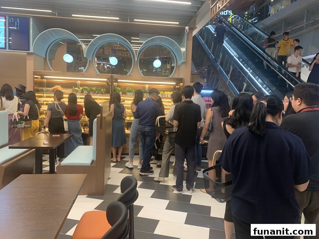 Customers browse fresh baked goods and food items inside Jie Huan Xi, a bustling shop with seating.