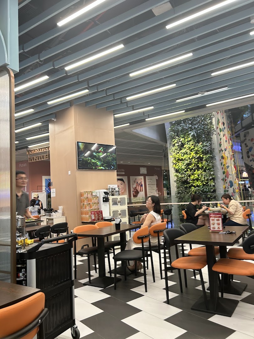 Customers seated at tables inside a modern eatery with a view of a vertical garden.