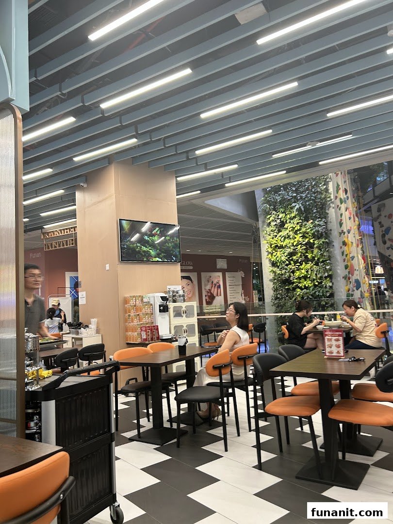 Customers seated at tables inside a modern eatery with a view of a vertical garden.