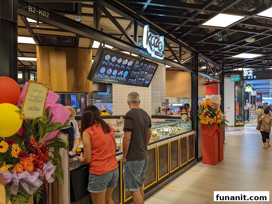 Kazo shop front in Funan mall, featuring customers, a display counter, and a digital menu board.