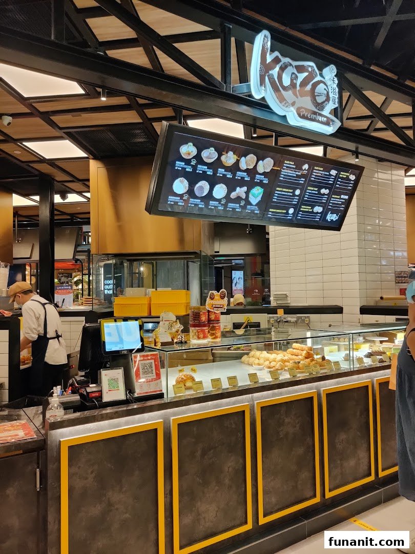 Interior view of Kazo bakery, featuring a display counter with pastries and a digital menu board.