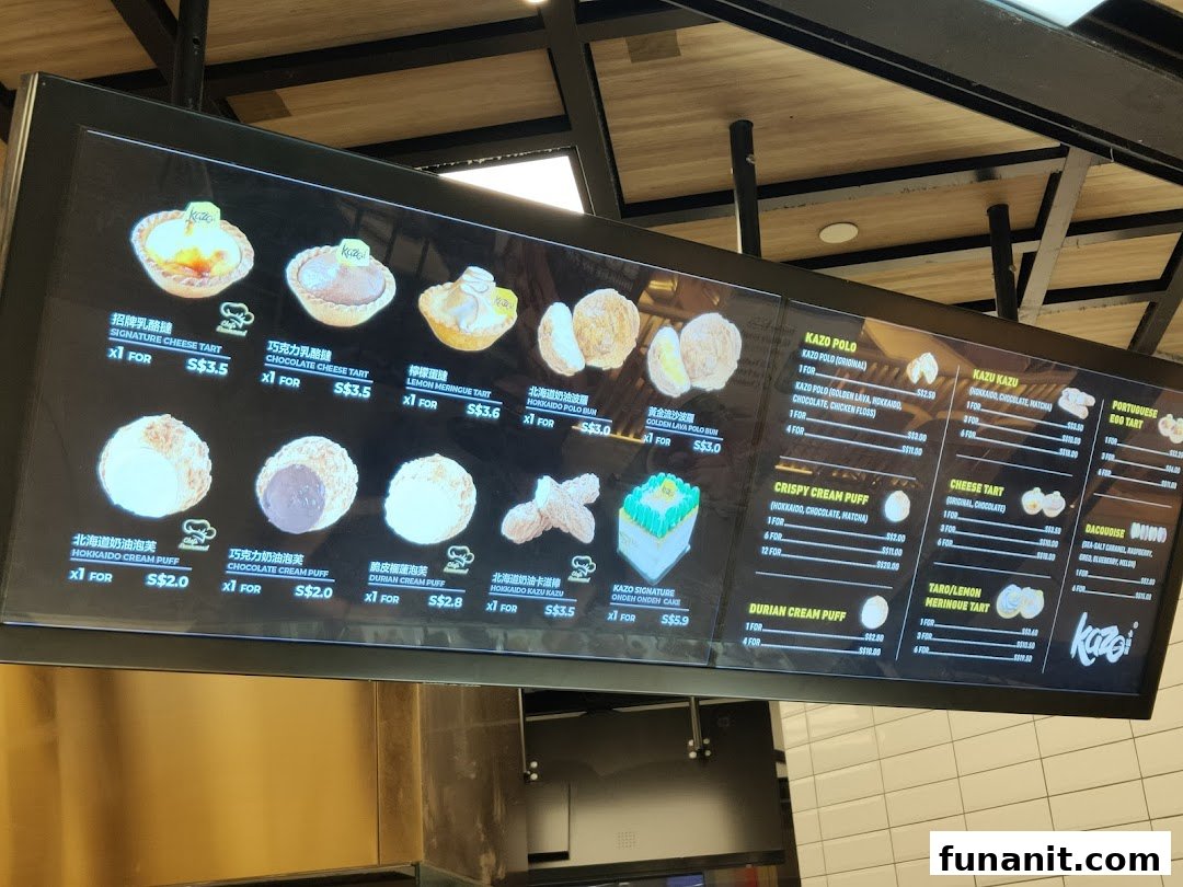 A digital menu board displaying various pastries, tarts, and cream puffs with prices at Kazo.