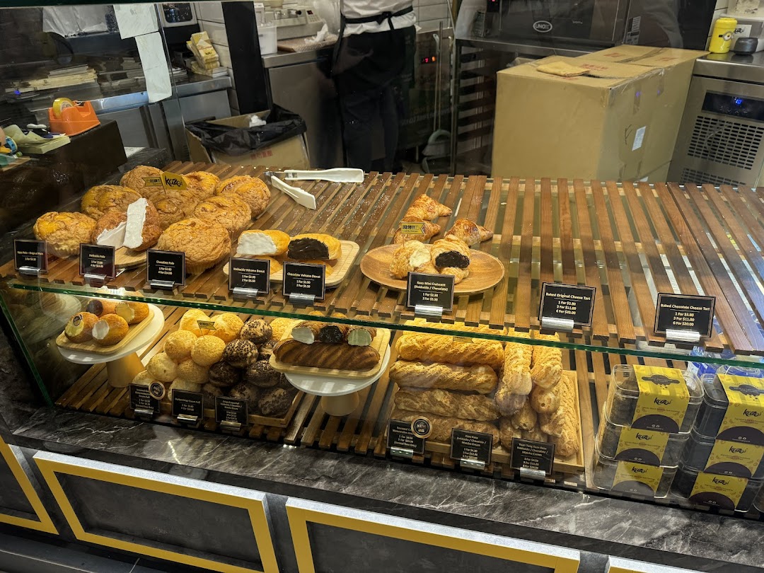 A vibrant display counter at Kazo bakery, showcasing a variety of freshly baked pastries, tarts, and puffs.