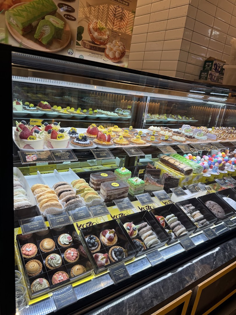 A vibrant display case filled with an assortment of delicious cakes, pastries, and tarts at Kazo.