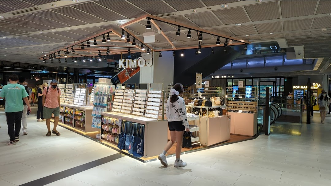 KIMOJ retail kiosk in a mall, showcasing accessories, sunglasses, and bags, with shoppers browsing.
