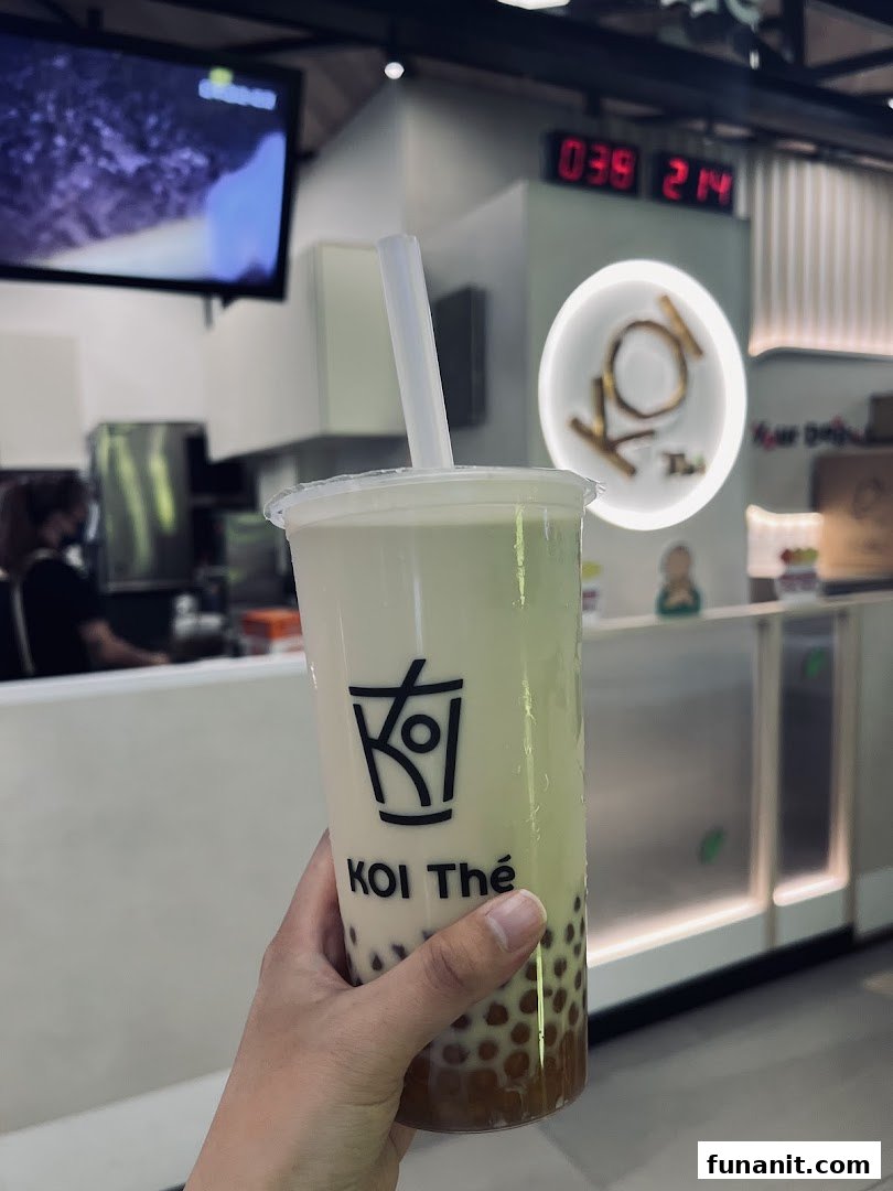 A hand holds a refreshing KOI Thé bubble tea cup inside the shop.