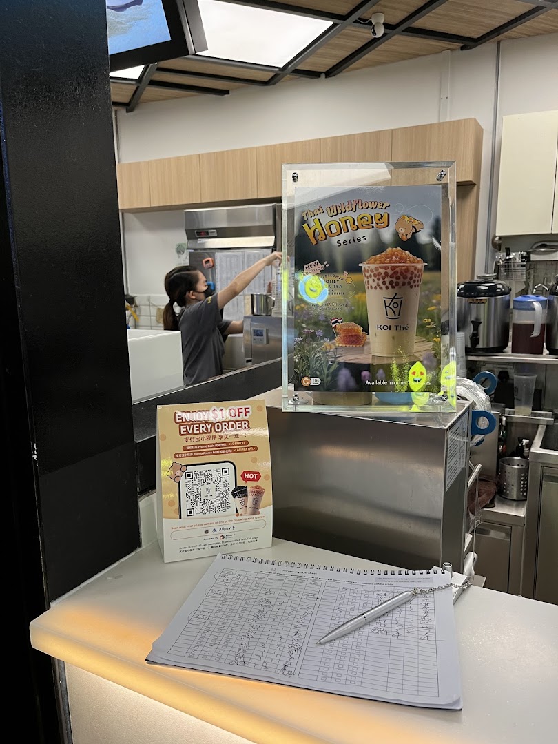 Interior view of KOI Thé Funan with staff, promotional display, and counter.