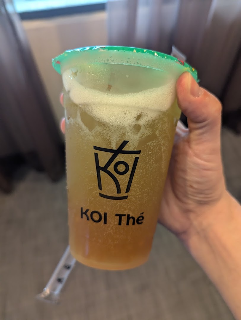 A hand holds a refreshing bubble tea drink from KOI Thé with its logo visible.
