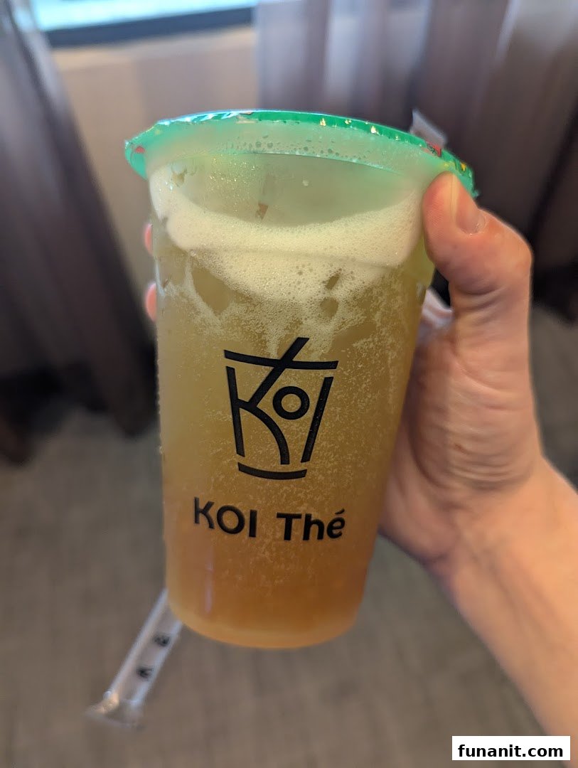 A hand holds a refreshing bubble tea drink from KOI Thé with its logo visible.