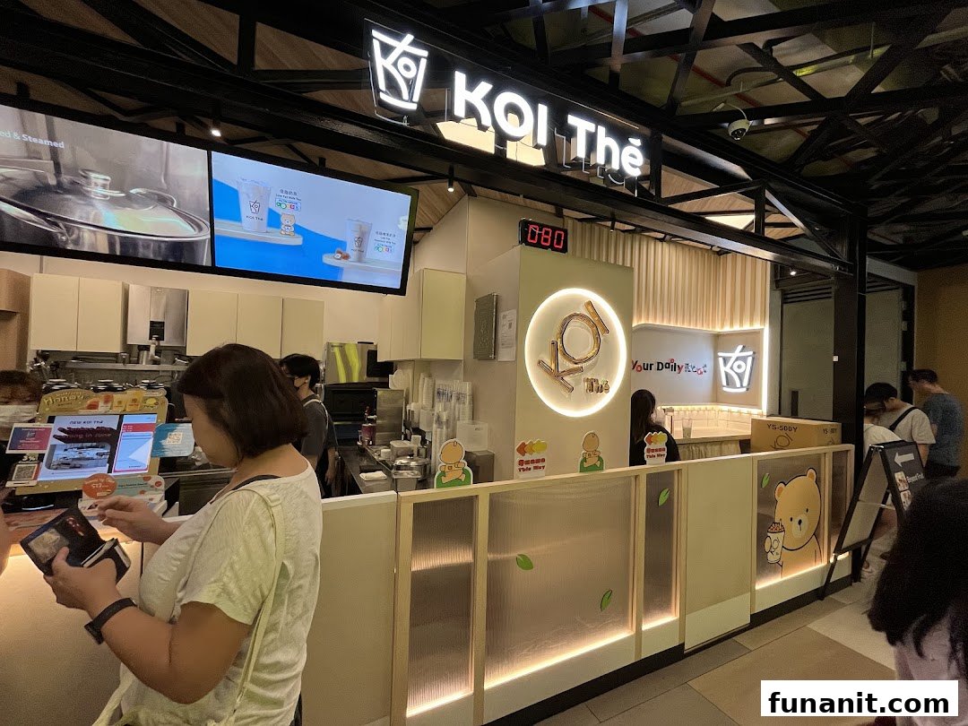 Customers at the KOI Thé counter, with digital displays showing beverages and branding.