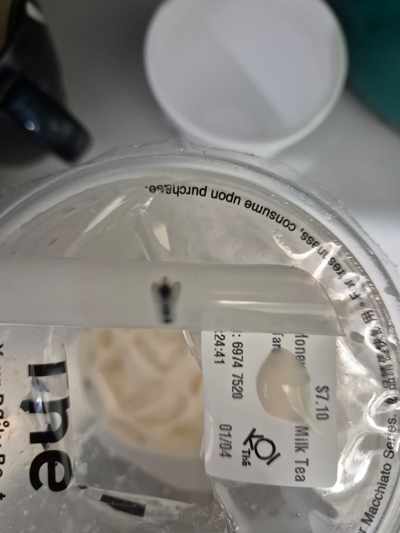 Close-up of a KOI Thé bubble tea cup with a product label showing "Milk Tea" and price.