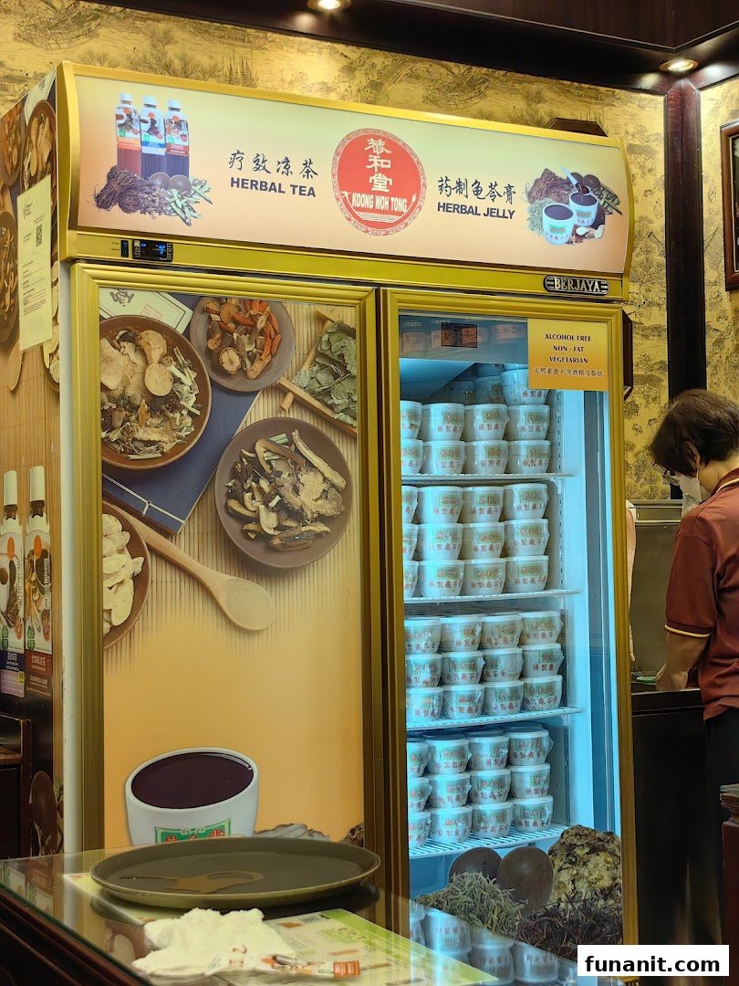A display fridge at Koong Woh Tong showcasing traditional herbal teas and jellies, with a staff member in the background.