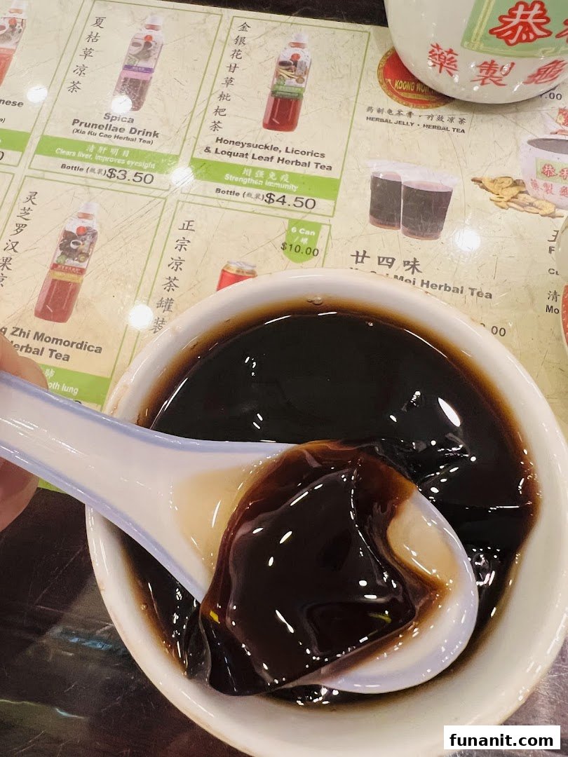 A close-up of Koong Woh Tong's herbal jelly with a spoon, set against a menu of traditional herbal drinks.
