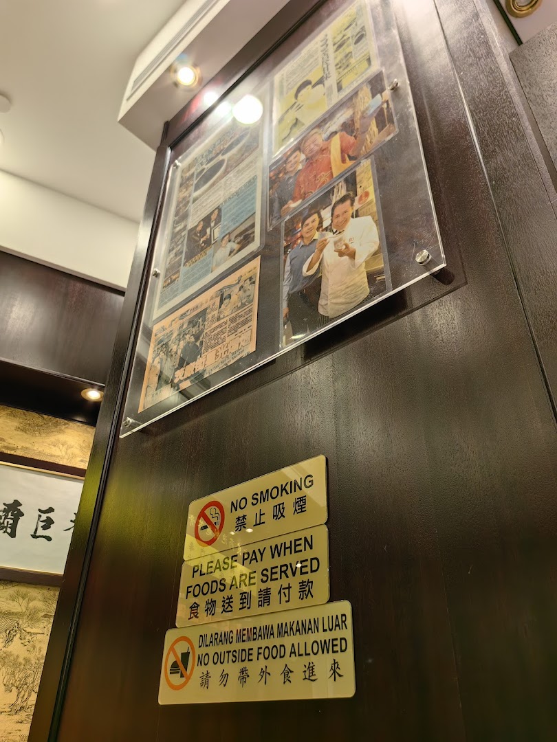An interior shot of Koong Woh Tong, featuring framed articles, photos, and operational signs on a wooden wall.