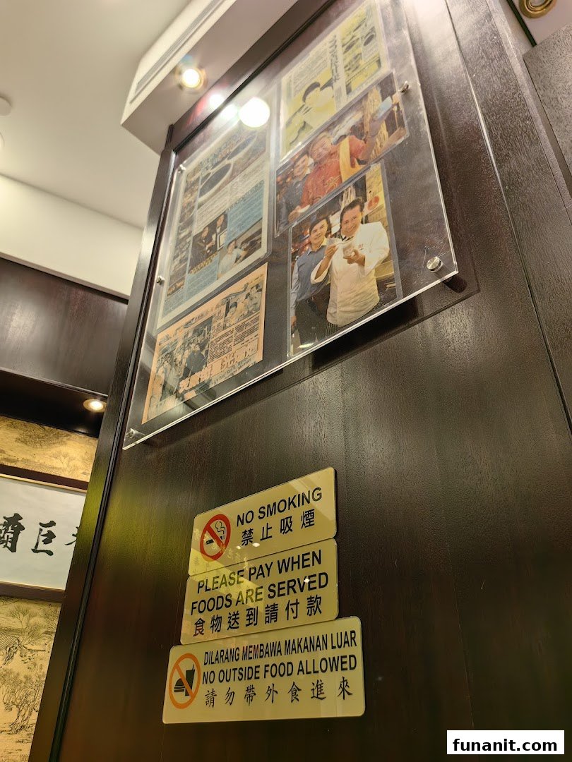 An interior shot of Koong Woh Tong, featuring framed articles, photos, and operational signs on a wooden wall.