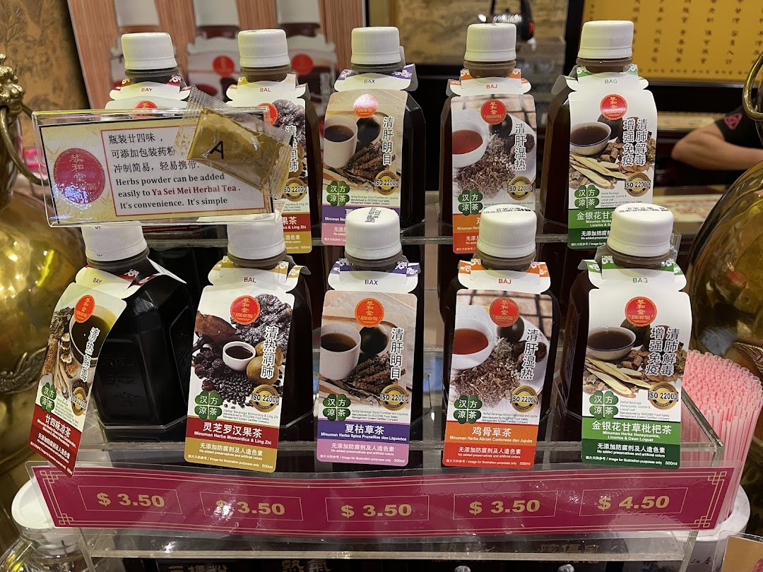 A display of various bottled traditional Chinese herbal drinks with prices at Koong Woh Tong.