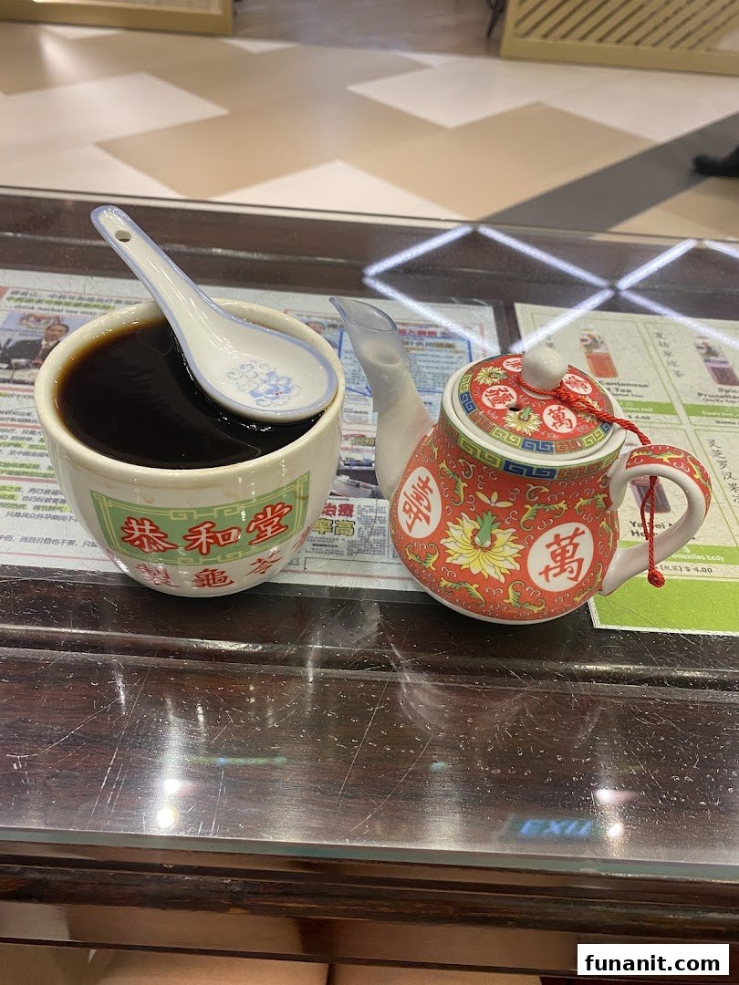 A traditional herbal jelly or tea in a cup with a spoon, alongside a decorative teapot on a wooden table.