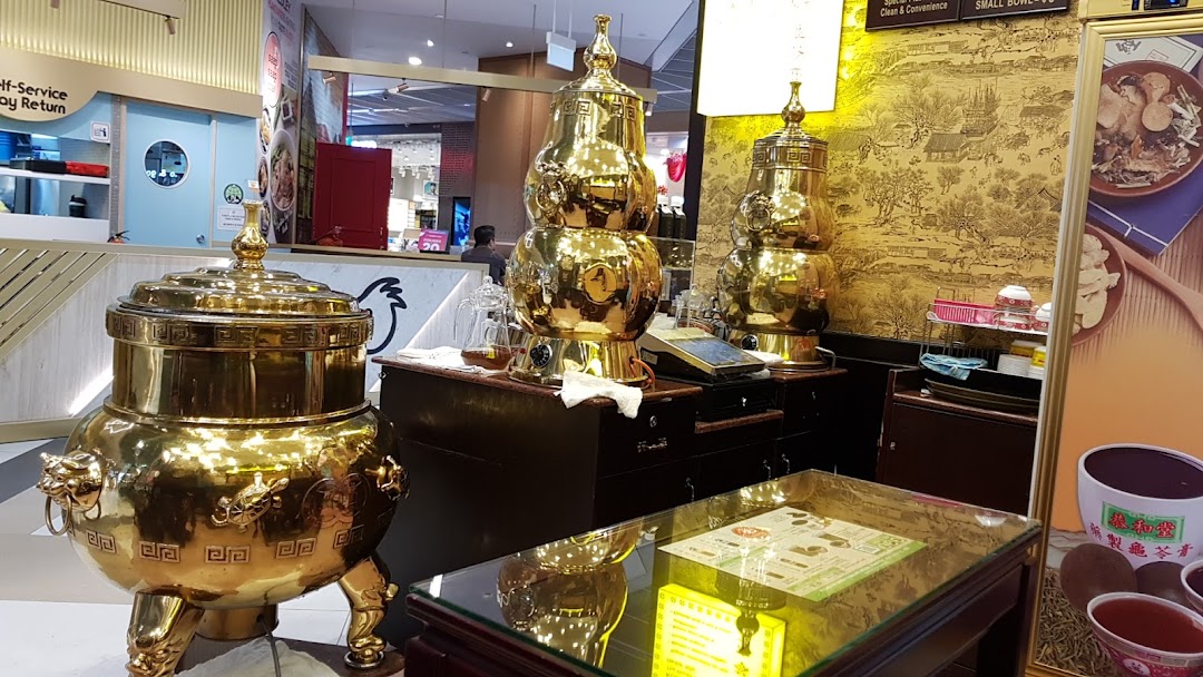 Interior view of Koong Woh Tong featuring large, ornate golden herbal tea dispensers and traditional decor.