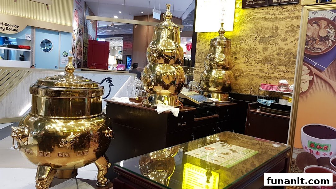 Interior view of Koong Woh Tong featuring large, ornate golden herbal tea dispensers and traditional decor.