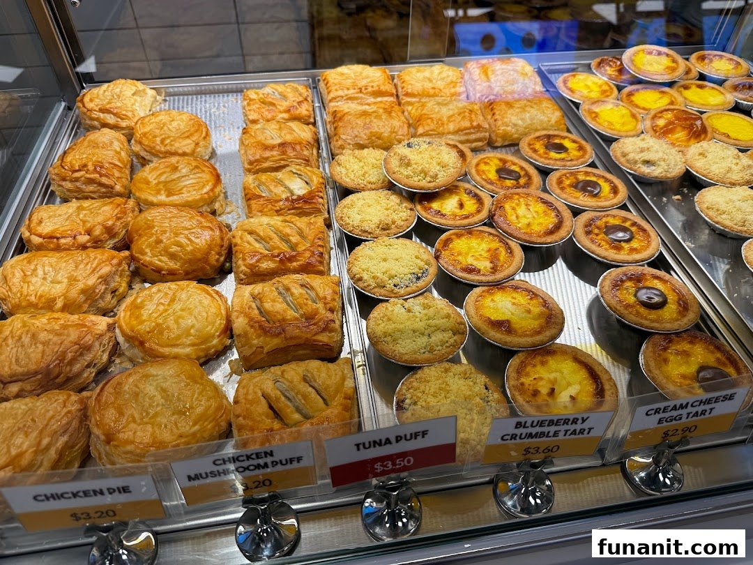 A vibrant display of freshly baked savory pastries and sweet tarts with visible price tags.