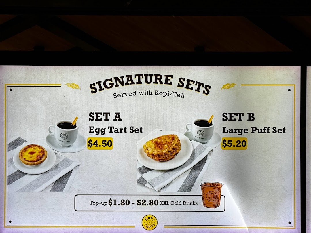 A menu board displaying Kopi Tarts' signature sets, including egg tart and large puff options.