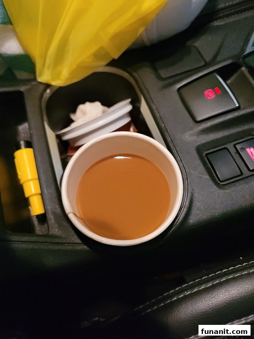 A cup of coffee or tea from Kopi Tarts in a car's cup holder, ready for a commute.