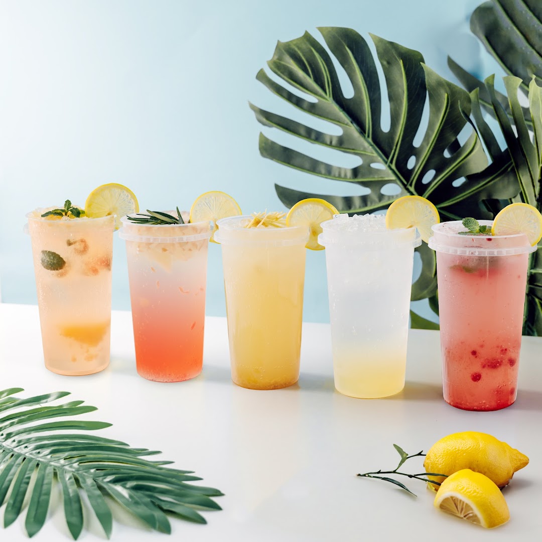 Five vibrant lemonade drinks with fresh fruit and garnishes, set against a tropical backdrop.