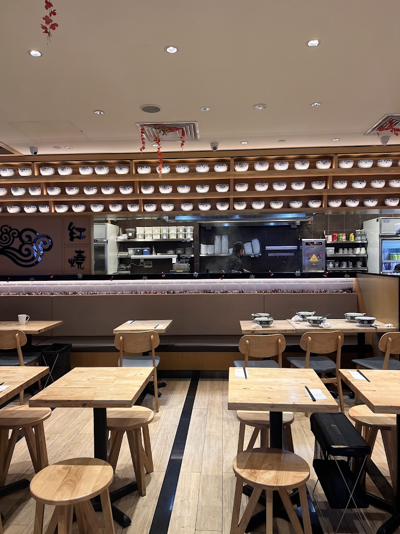 Interior view of LeNu Chefs Wai Noodle Bar, showing dining area with wooden tables and an open kitchen.