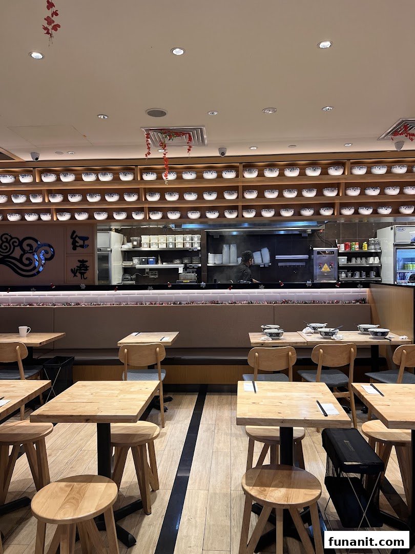 Interior view of LeNu Chefs Wai Noodle Bar, showing dining area with wooden tables and an open kitchen.