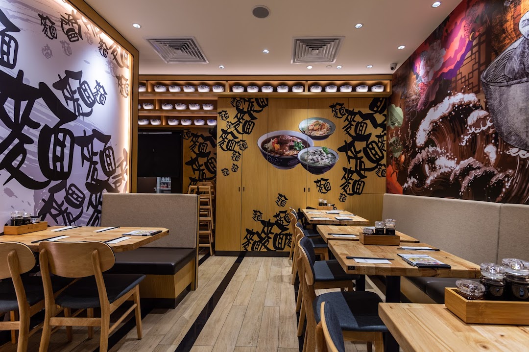 A cozy interior view of LeNu Chefs Wai Noodle Bar, featuring wooden tables, banquettes, and vibrant wall art.