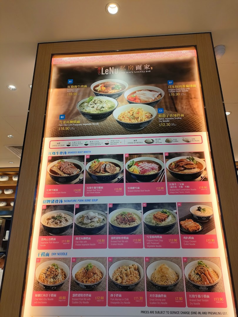 A brightly lit digital menu board displaying various noodle dishes with images and prices.
