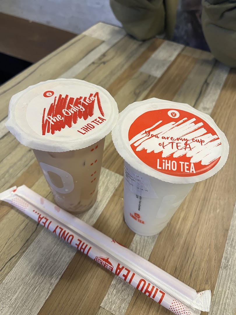 Two refreshing LiHO TEA bubble tea drinks with straws on a wooden table.