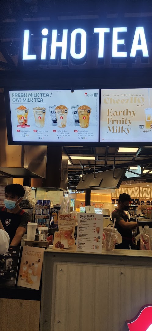 A bustling LiHO TEA counter with staff preparing drinks and digital menu boards displaying offerings.