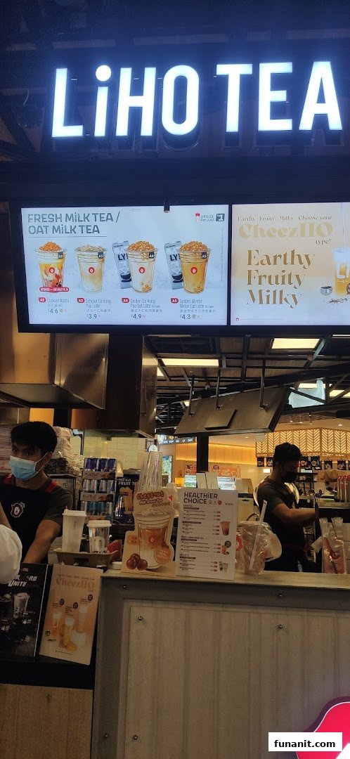 A bustling LiHO TEA counter with staff preparing drinks and digital menu boards displaying offerings.